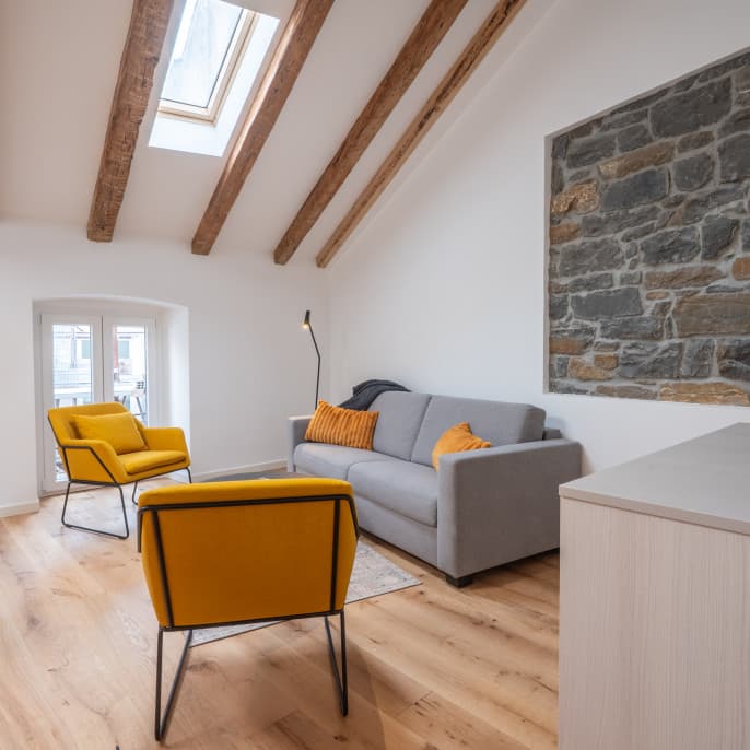 Abgebildet ist das Wohnzimmer eines Comfy Apertments in den URBANAUTS STUDIOS Ginnastica, das die Gemütlichkeit mit der erhaltenen historischen Backsteinwand zeigt.