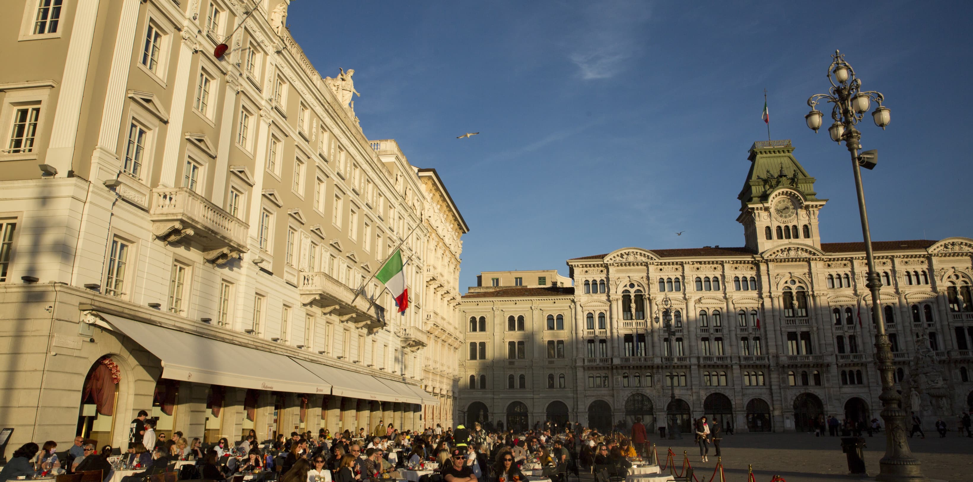 The main Piazza at the center of Trieste. People are enjoying a coffee in the sun.