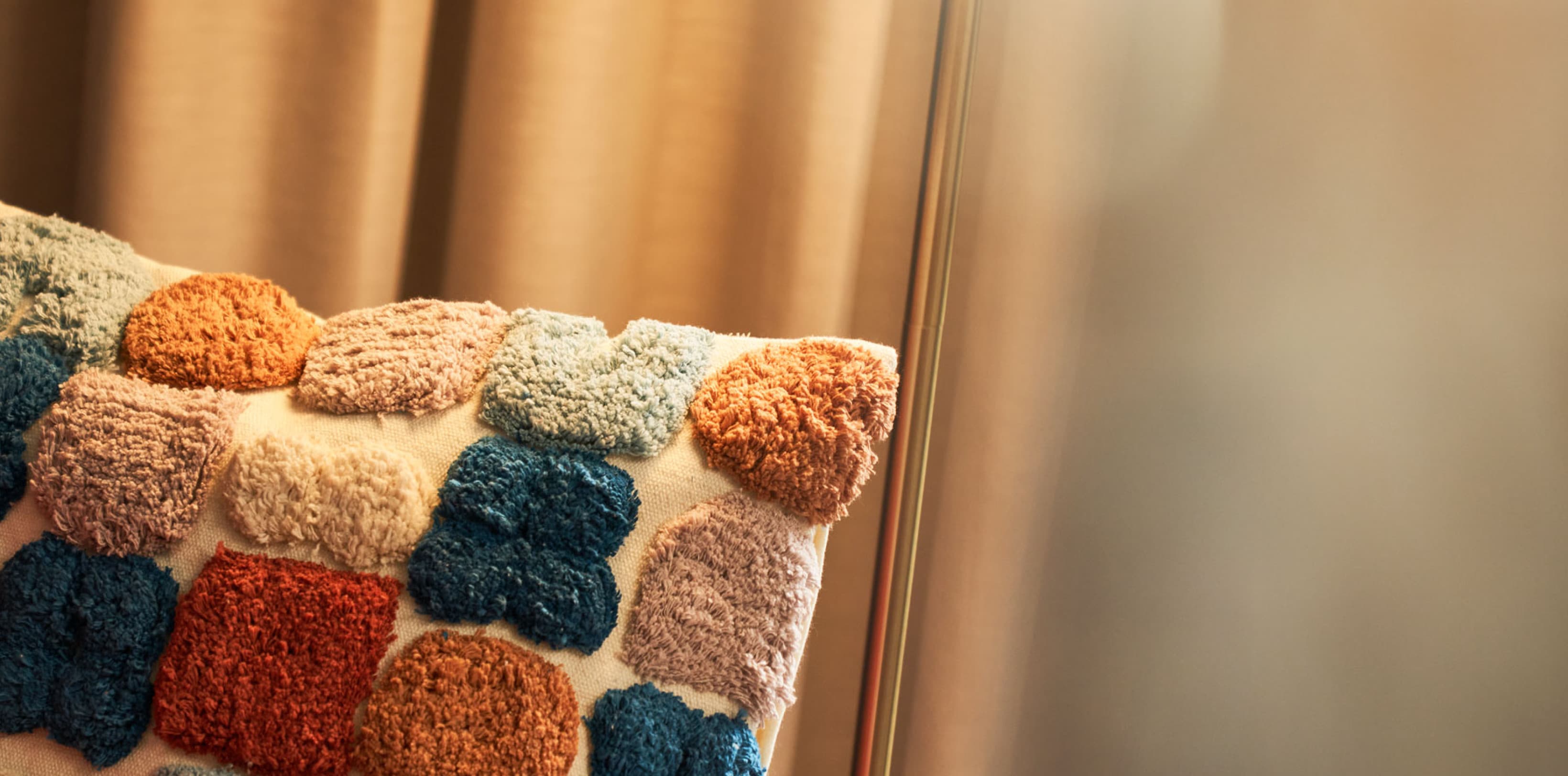 Detail picture of a pillow on a chair in the apartments of URBANAUTS STUDIOS Ginnastica, which has different colours.