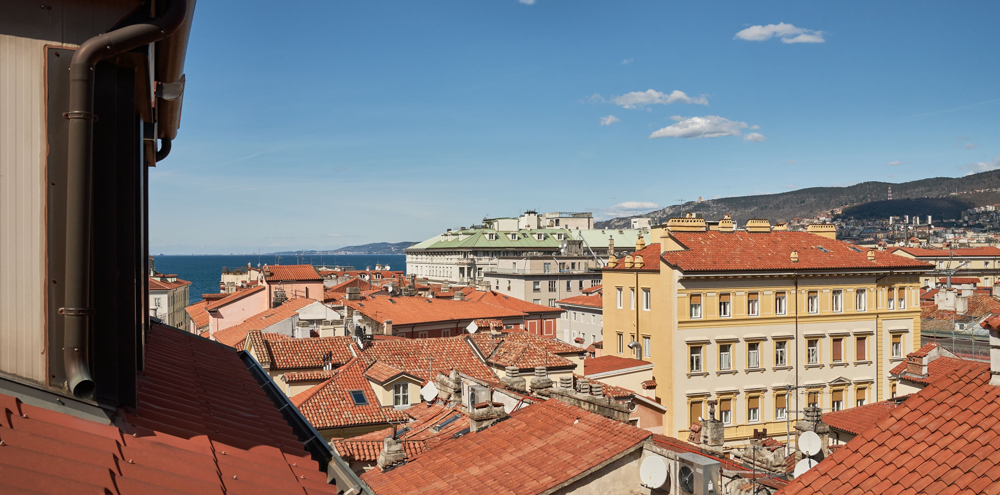 View over the rooftops of Trieste. The red iconic roof guide the view towards the harbour of Trieste.