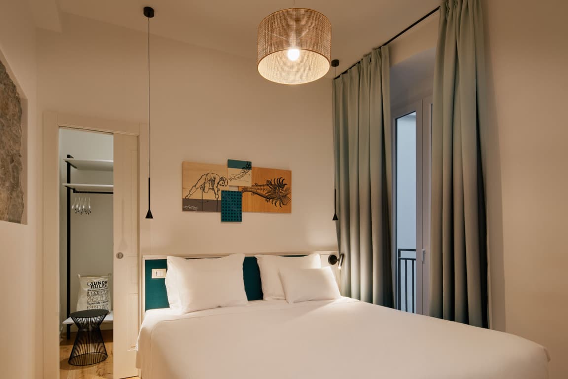 Zu sehen ist das Schlafzimmer eines geräumigen Studios mit begehbarem Kleiderschrank und Blick auf den Innenhof.