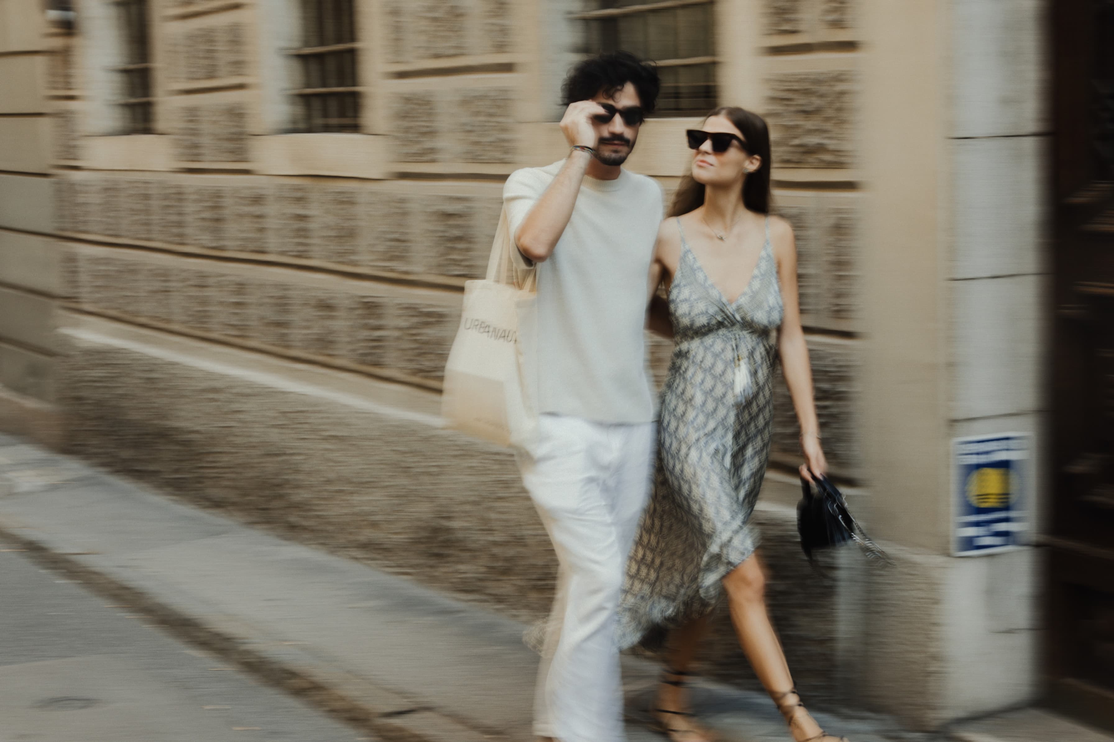 A couple is exploring the streets of Trieste with a historic building in the back.