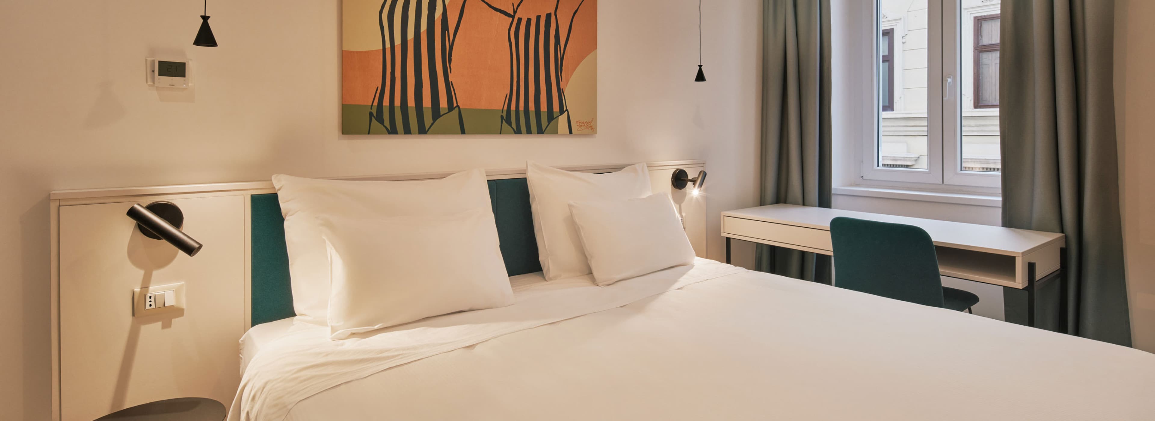 Das Schlafzimmer wird durch die Kunstwerke im Hintergrund ergänzt, die das Thema Ginnasgica widerspiegeln, das von Sport und Gymnastik inspiriert ist. Das Doppelbett bietet Platz für zwei Personen und die Farben sind in warmem mediterranem Stil gehalten.