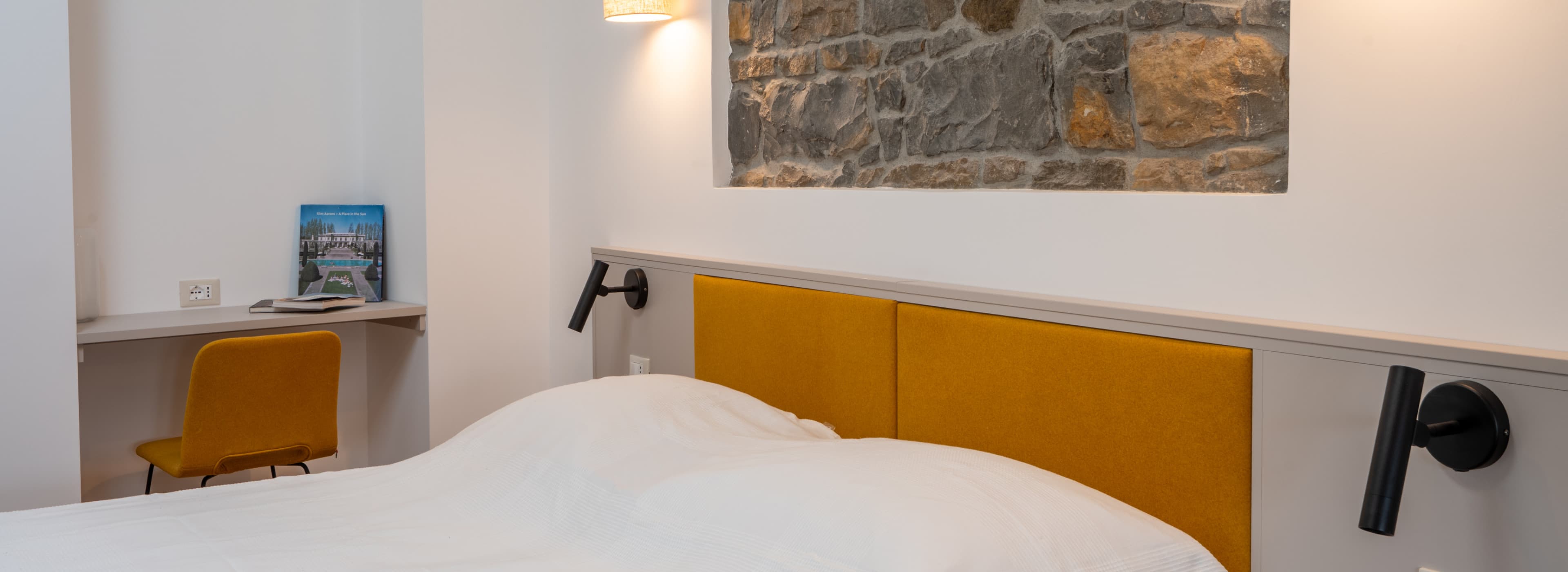 Blick in das Schlafzimmer mit einer authentischen Steinmauer hinter dem Doppelbett.