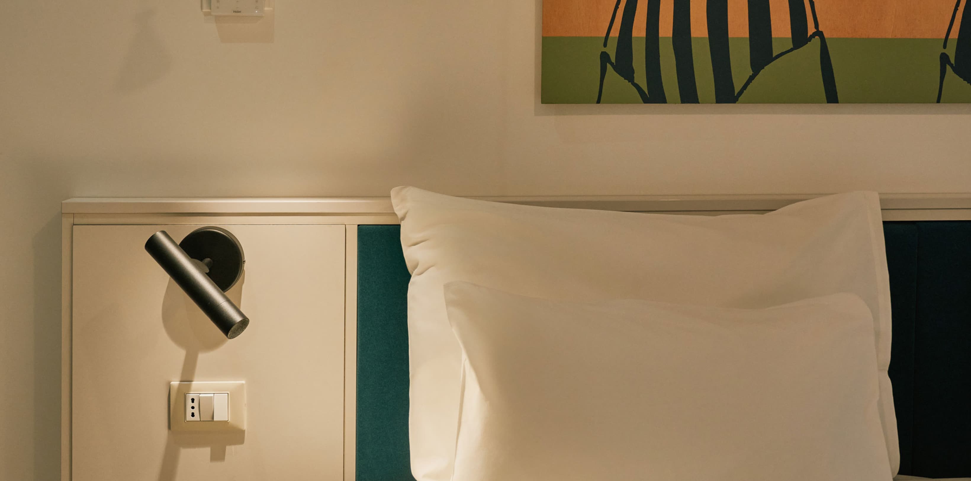 Sen ist eine Detailaufnahme des Schlafzimmers des Comfy Studios, die die Kunstwerke im Hintergrund sowie einen Teil des Doppelbetts zeigt.