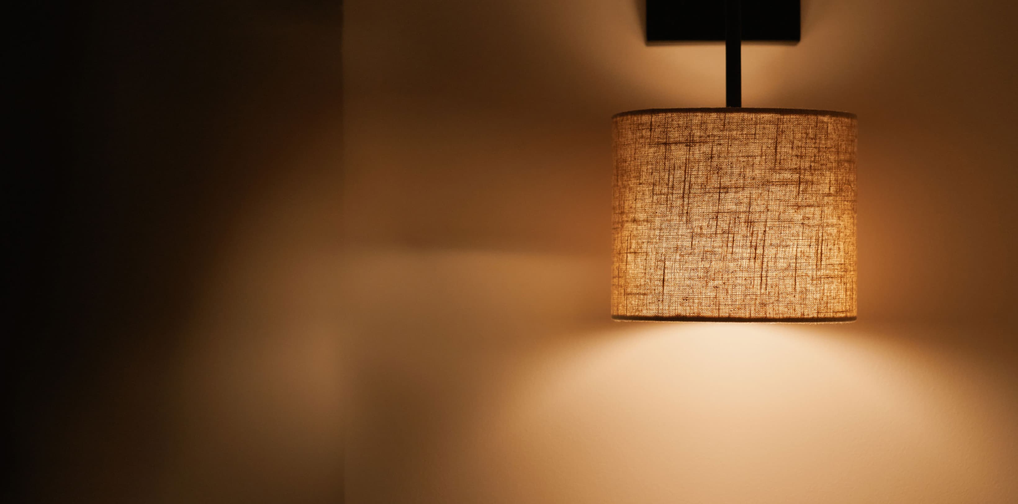 Gezeigt wird eine Detailaufnahme einer Lampe, die in gedämpftem Licht leuchtet. Sie verdeutlicht die Eleganz und die urbane Chic-Atmosphäre des Comfy-Studios.