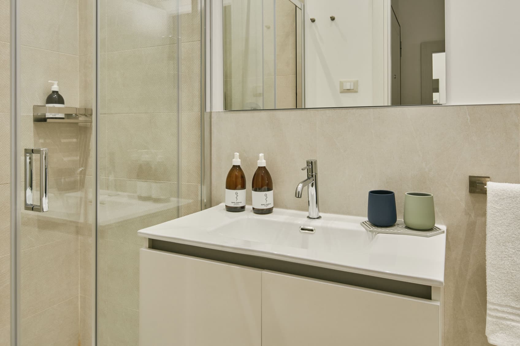 Nella foto è raffigurato il bagno del Comfy Studio, che mostra la doccia con gradino sul lato sinistro e il lavandino sul lato destro. Ogni appartamento è fornito di prodotti per la cura personale gratuiti per migliorare il soggiorno degli ospiti.