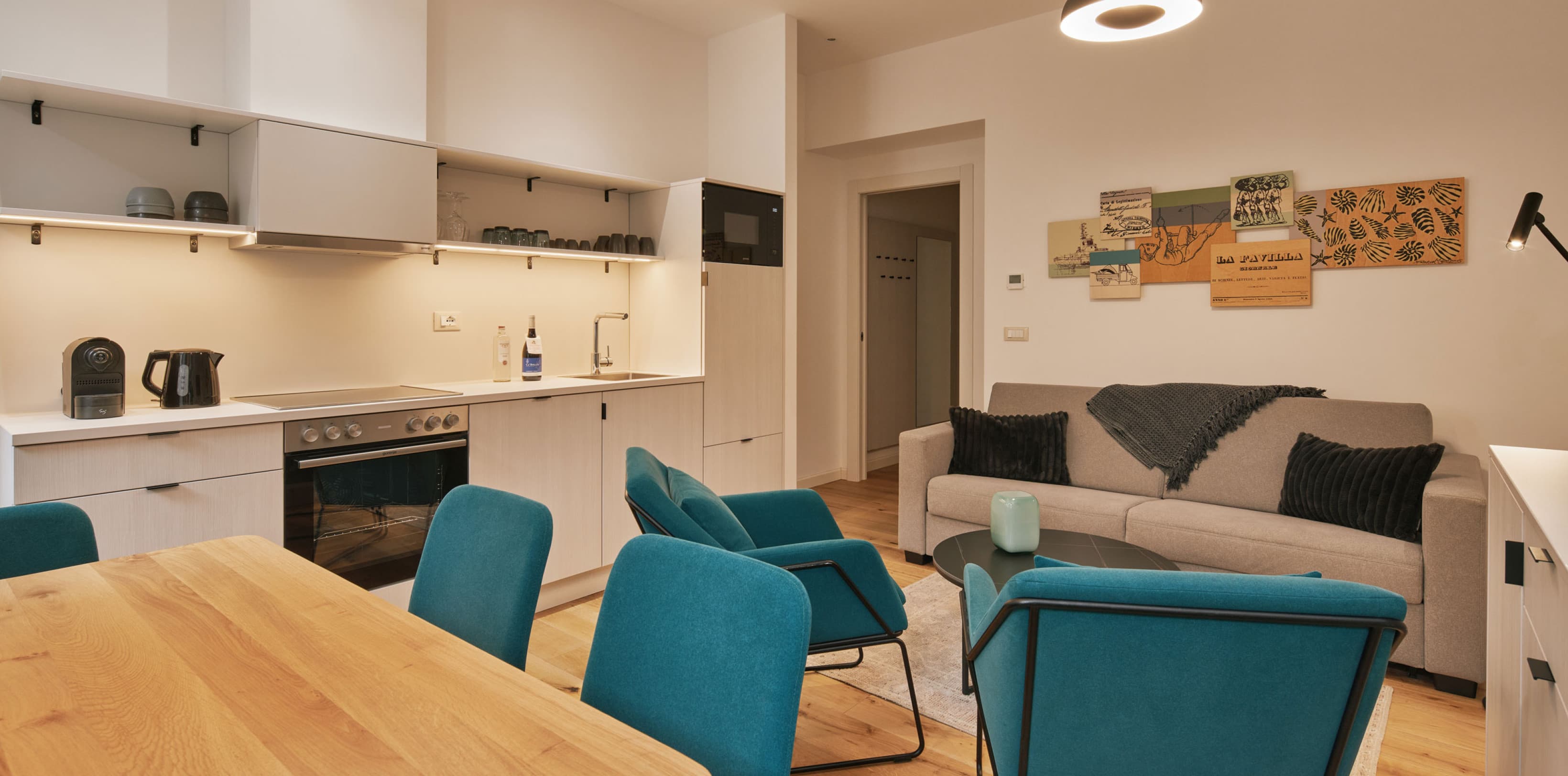 Zu sehen sind die Küche und das Wohnzimmer des Comfy Studio. Die geräumige Wohnung verfügt über eine voll ausgestattete Küche mit Platz für einen Esstisch sowie eine ausziehbare Couch, die als zusätzliches Bett genutzt werden kann.