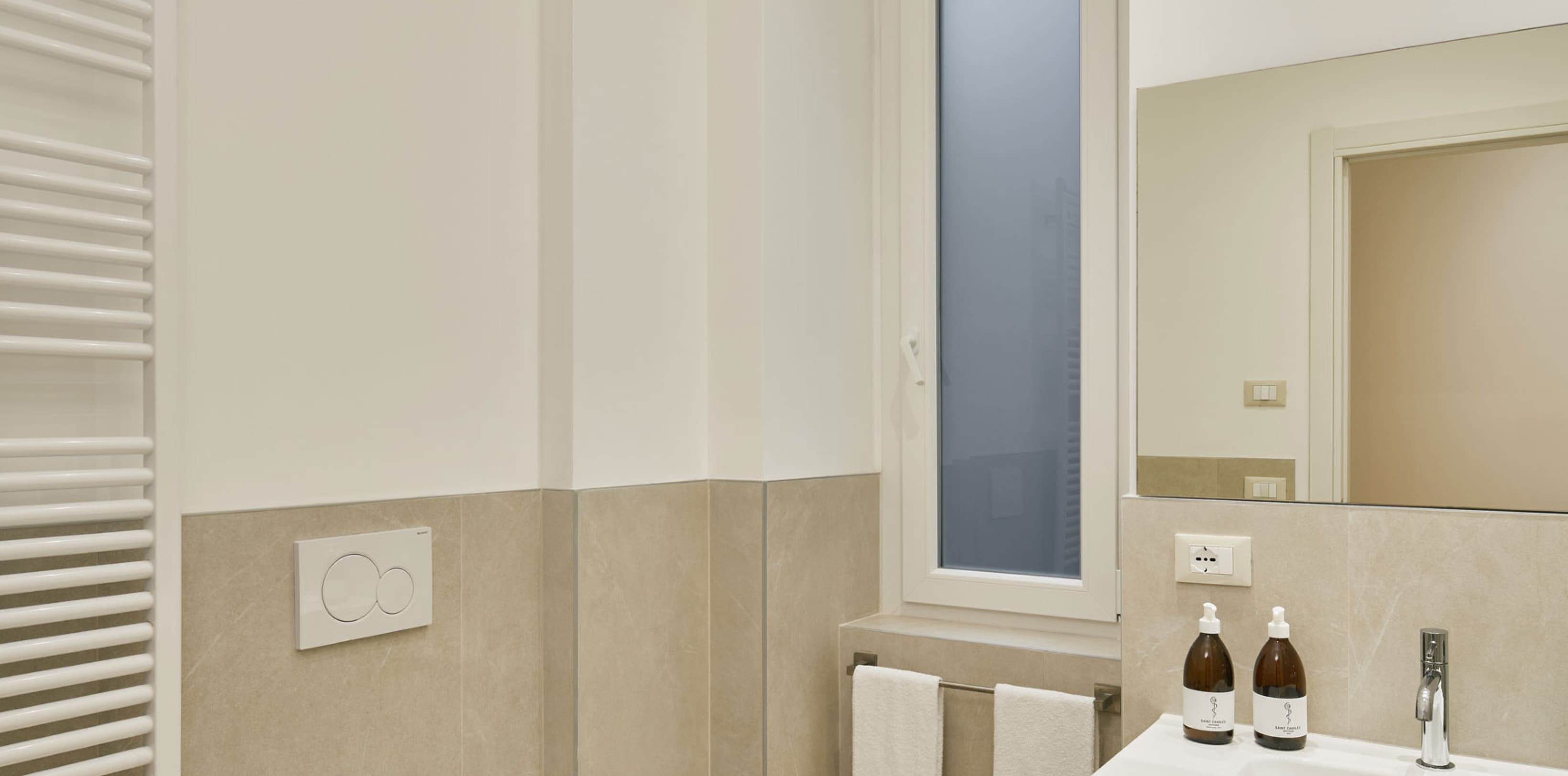 Shown is the bathroom of a spacy studio with a toilet on the left and sink on the right side.