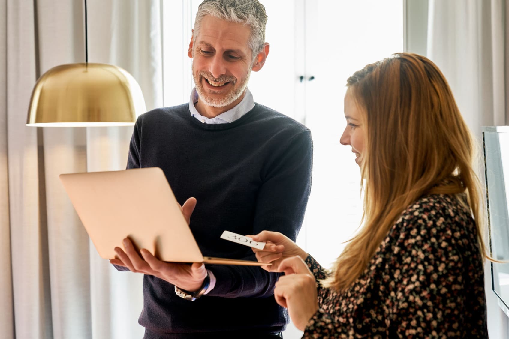 A man and a woman are talking in a business setting at the URBANAUTS STUDIOS and the man is showing the man something. URBANAUTS is always reachable by phone and email in all countries.