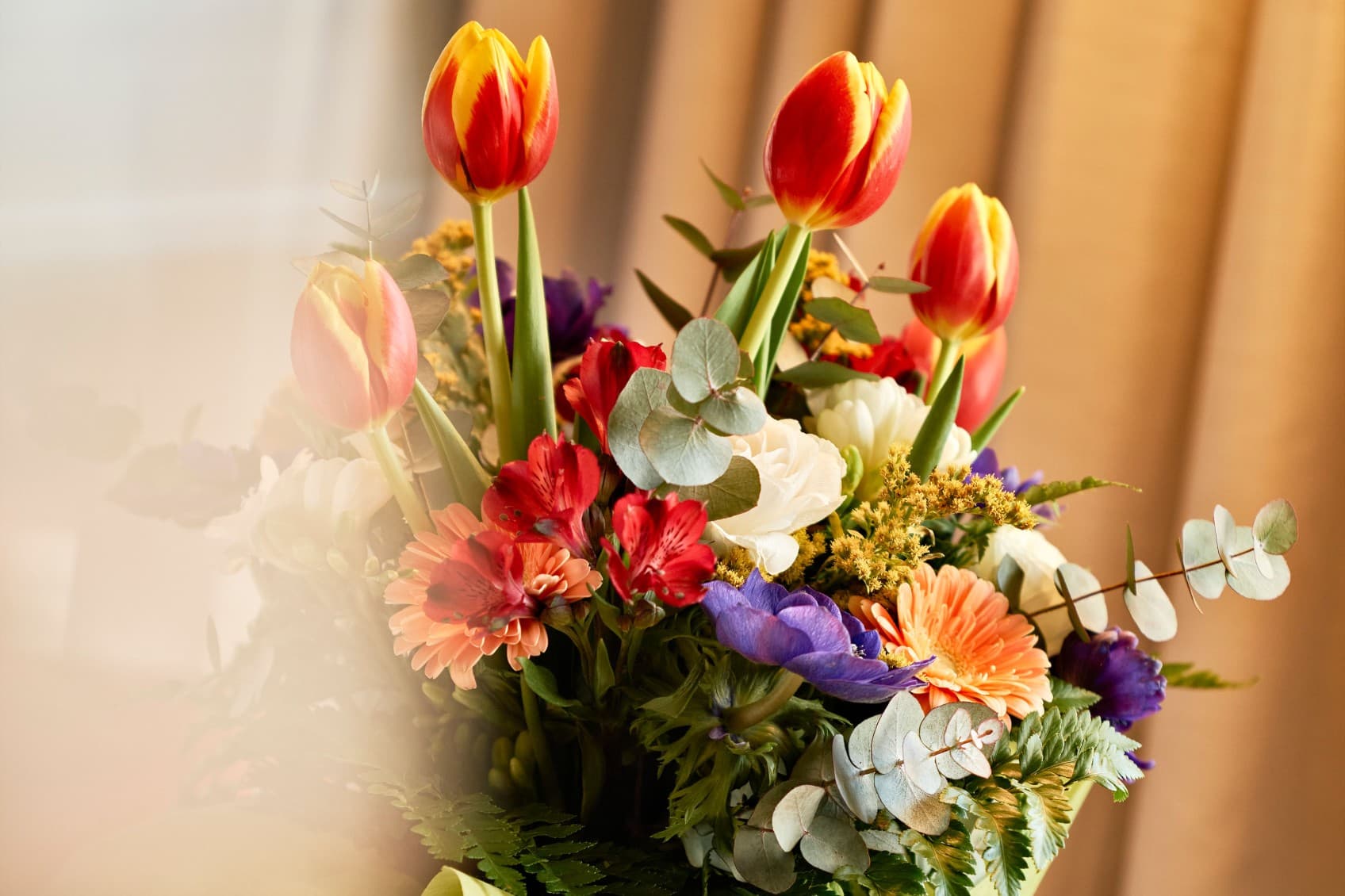 Auf dem Bild sehen Sie einen schönen Blumenstrauß mit einer Vielzahl von Blumen, darunter auch Tulpen, die Sie zu Ihrem Aufenthalt bei URBANAUTS hinzufügen können.