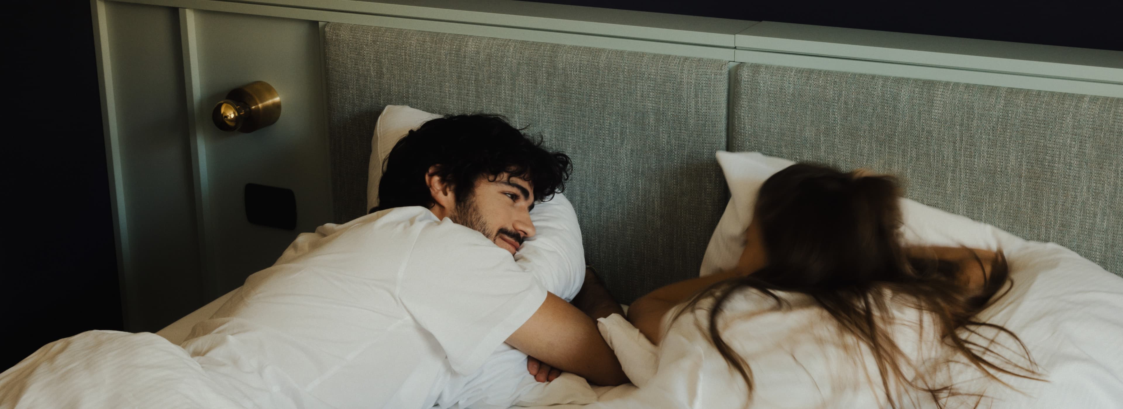 Pictured is a young couple, that is lying in bed, relaxing, talking and enjoying the morning at the URBANAUTS STUDIOS Ginnastica.