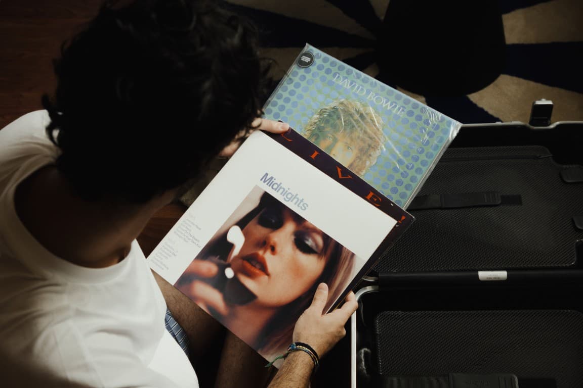 Detailed shot of a guy holding different different records. The records are in focus and the background is slightly darker and blurred.
