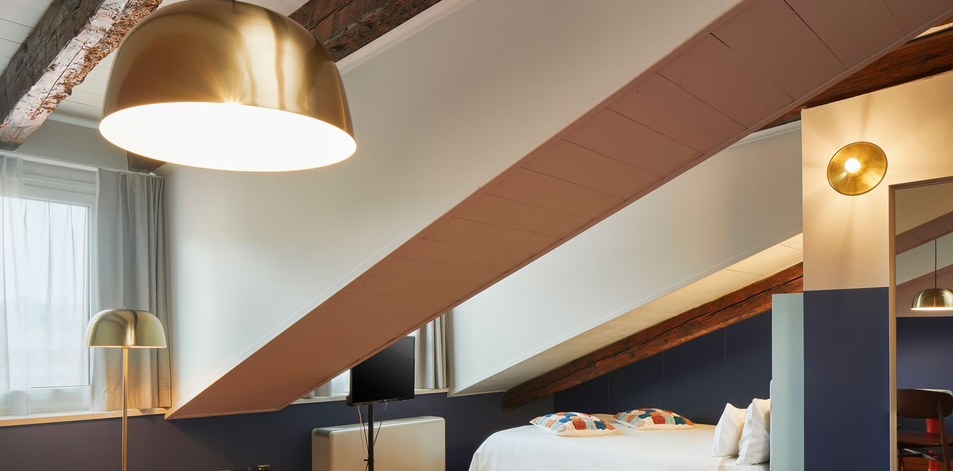 Cozy Studio 605, view of the bed under the roof and the rest of the room.