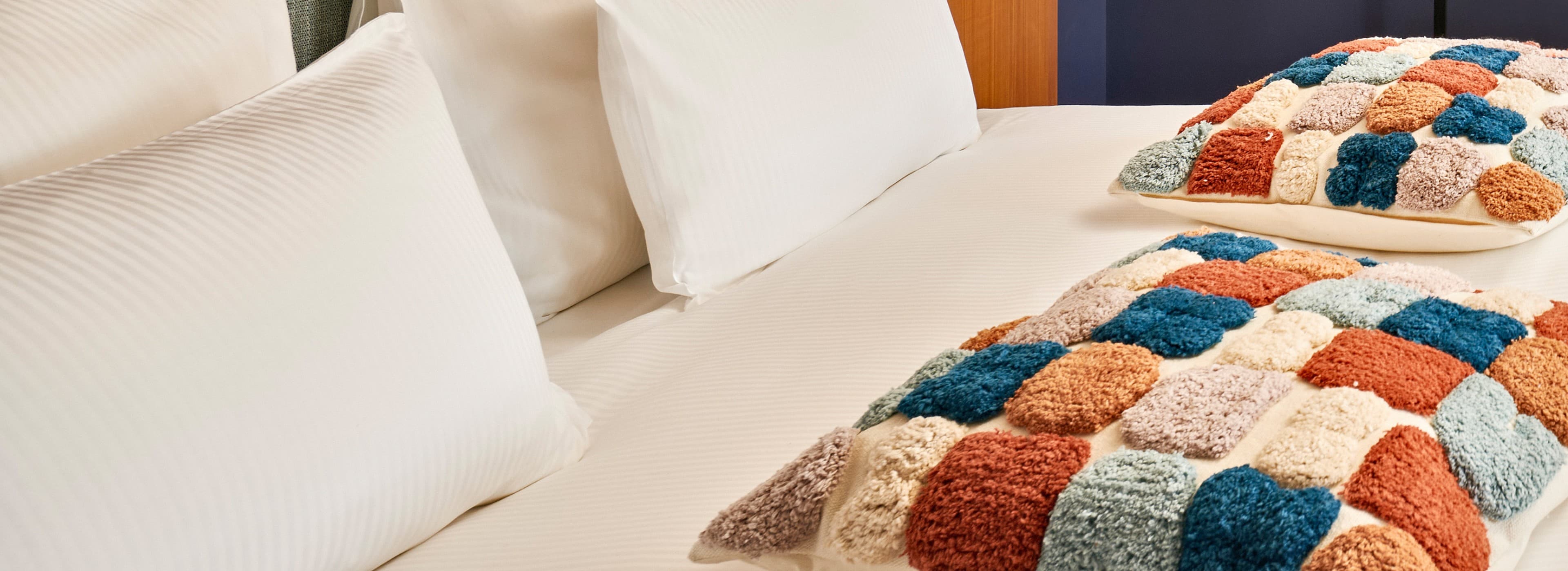 A detailed picture of a bed at the URBANAUTS STUDIOS Ginnastica, which also features the colourful cushions.