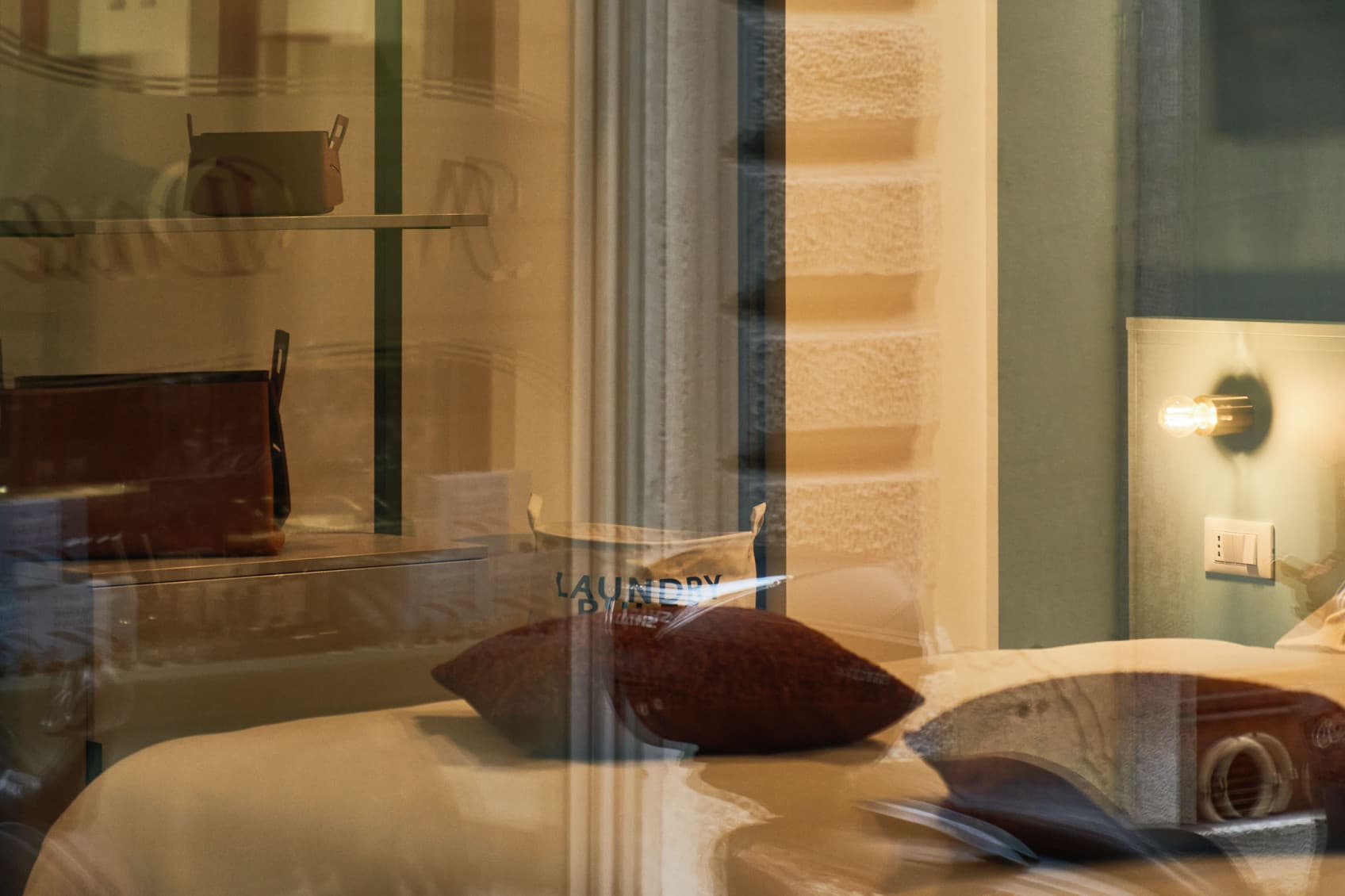View through the outside window into the bedroom. You can see the bed, as well as the open concept room in the back with an open closet.