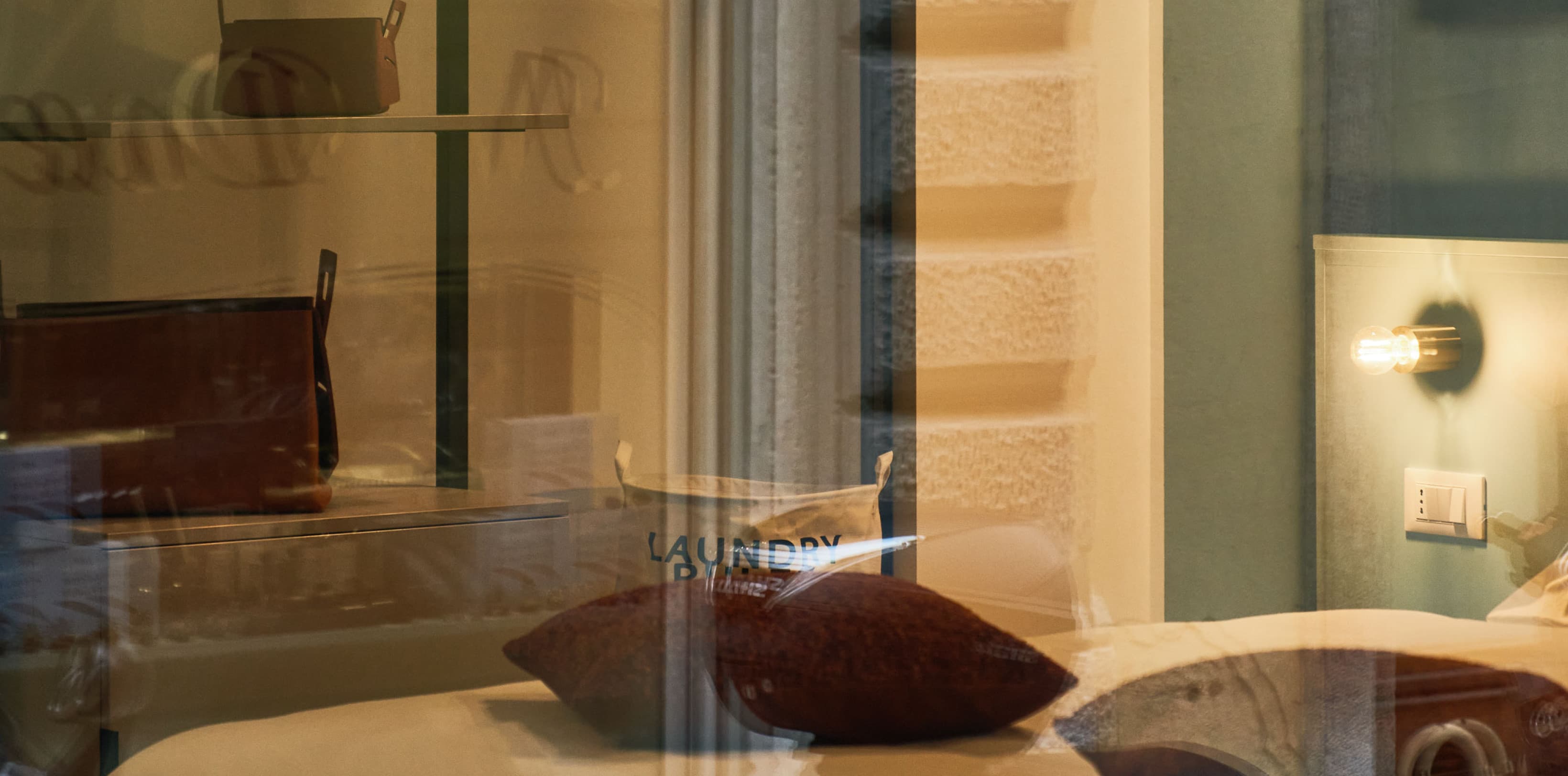 View through the outside window into the bedroom. You can see the bed, as well as the open concept room in the back with an open closet.