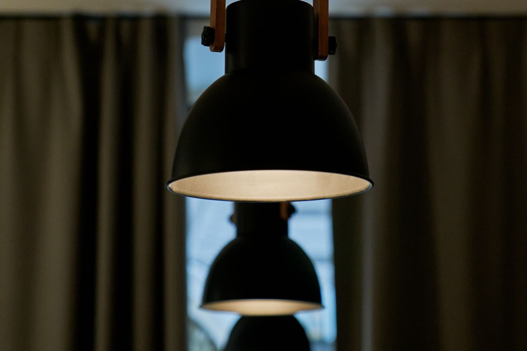Seen are three indusrial lamps in a row hanging in the street lofts. They are part of the design aspect, that shows the individuality of the spaces.